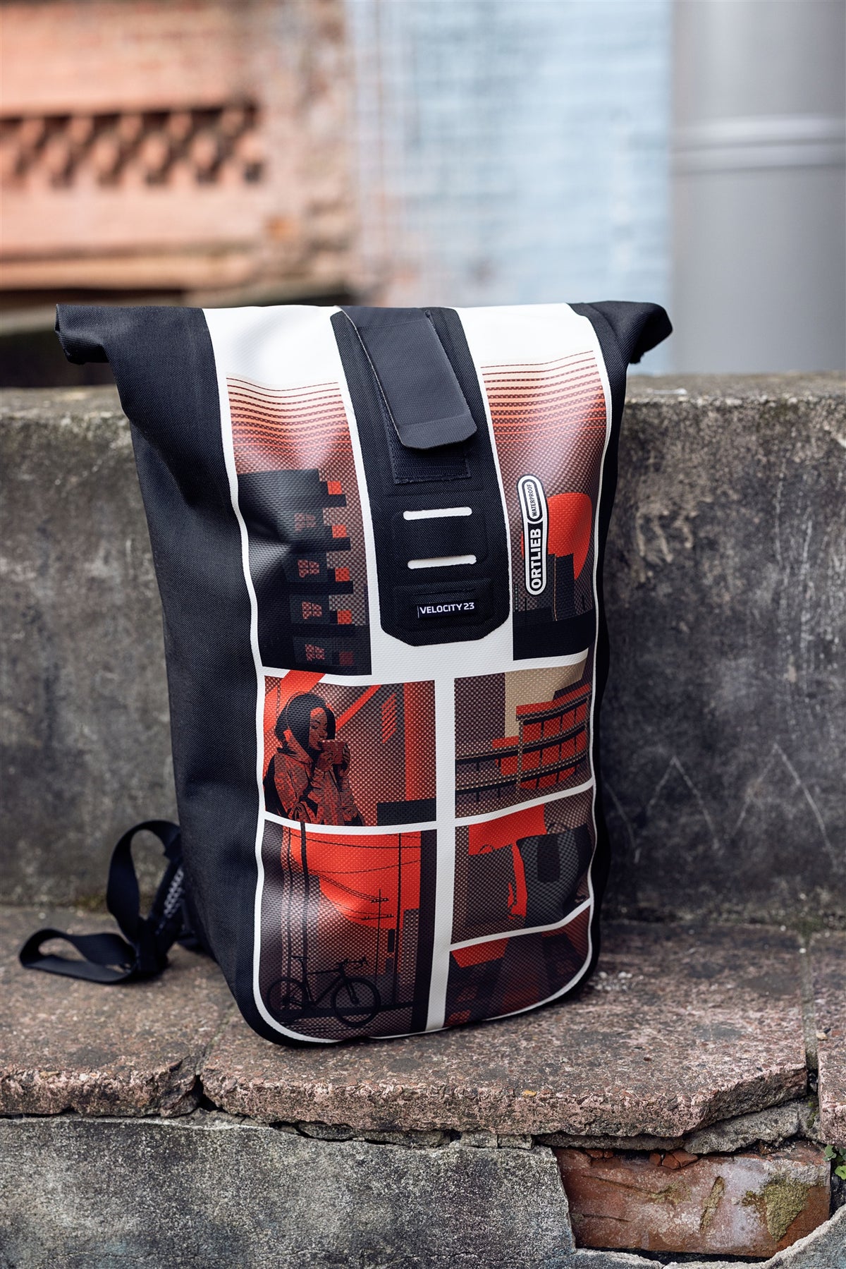 Woman with ORTLIEB Velocity Design backpack sitting on wall in urban brick setting