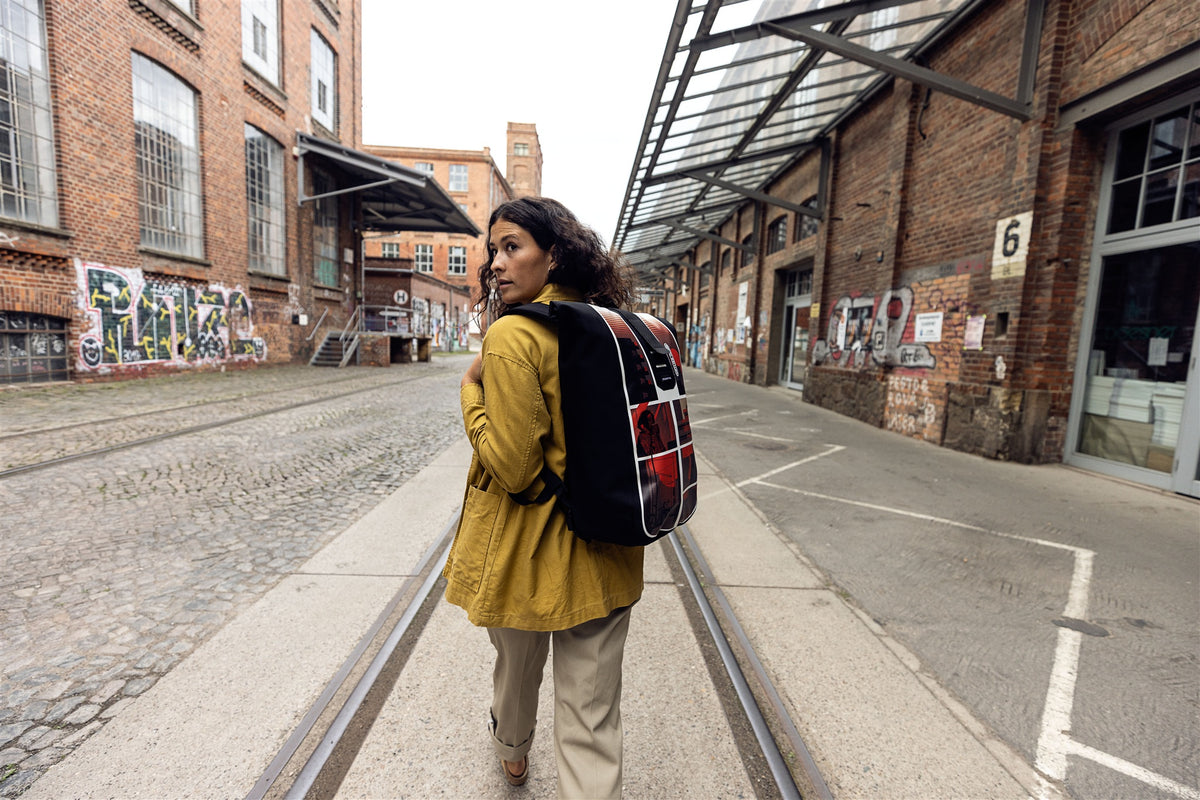 Woman wearing ORTLIEB Velocity Design backpack in industrial area with graffiti on walls
