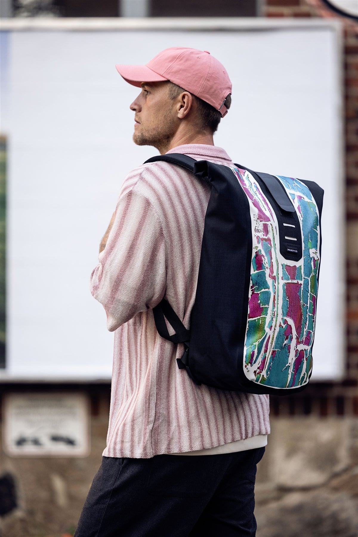 Back view of man wearing ORTLIEB Velocity Design backpack in front of brick building