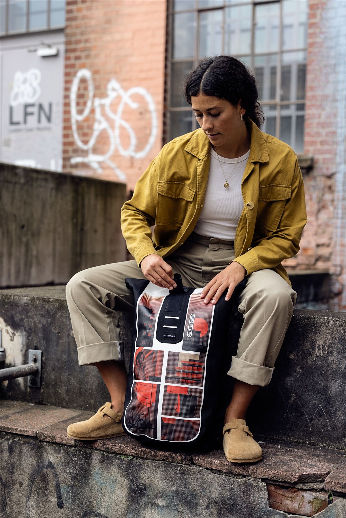 ORTLIEB Velocity Design backpack with red city motif placed on rough concrete wall